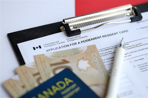 Application for a Canadian Permanent Resident Card with Canadian currency and a pen.