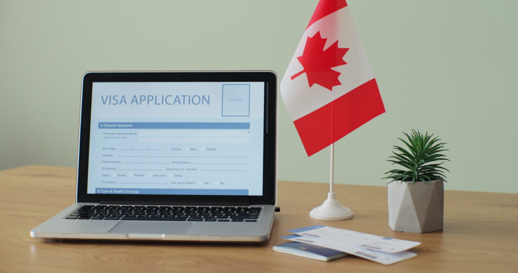 Online Canada Visa Application showing on a laptop computer screen sitting on a desk. Travelling abroad or immigration concept.